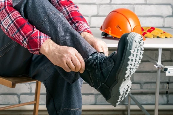 Person zieht Arbeitsschuhe an